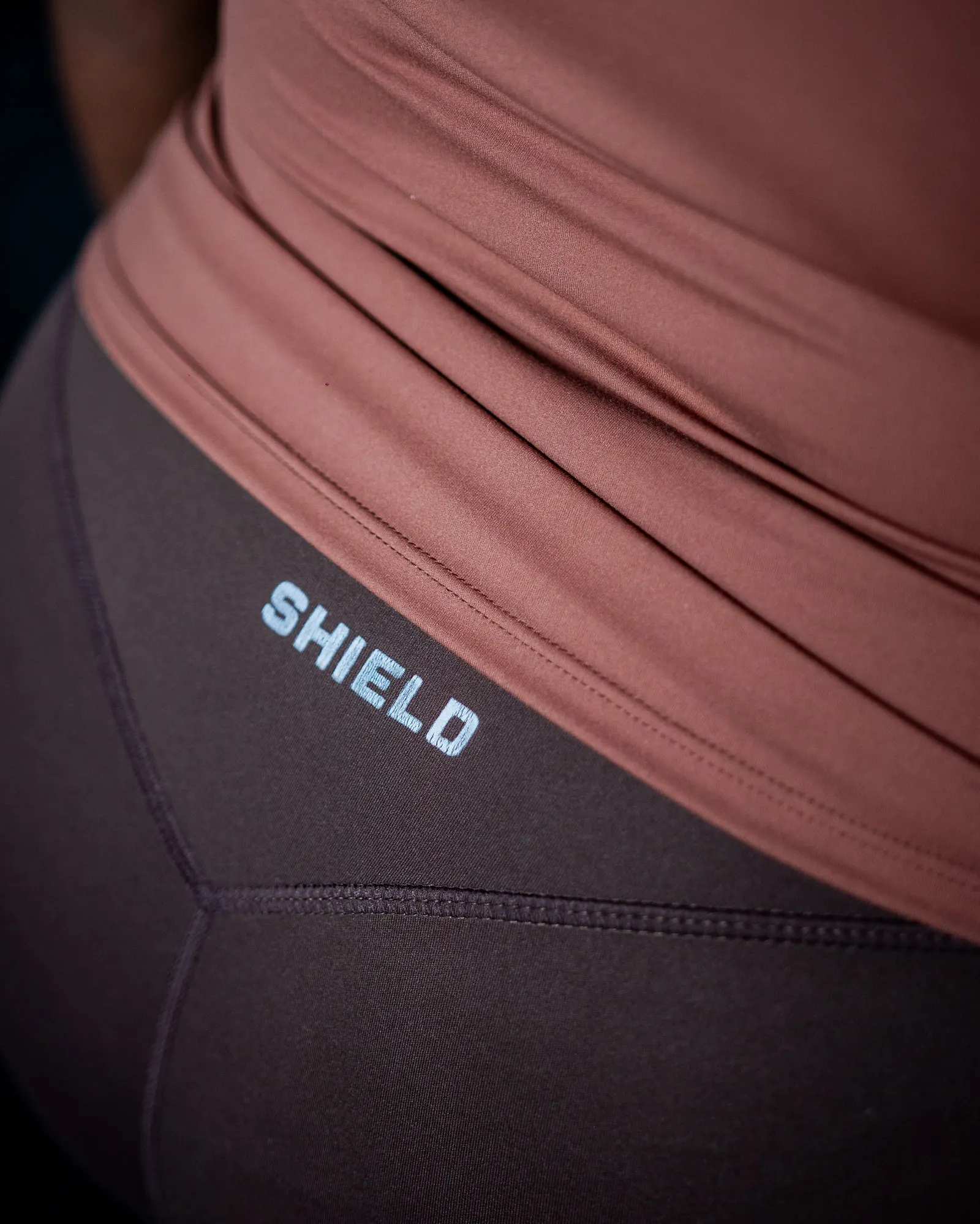 The Shield logo on the waistband of the Flow Flare Leggings in Espresso Brown